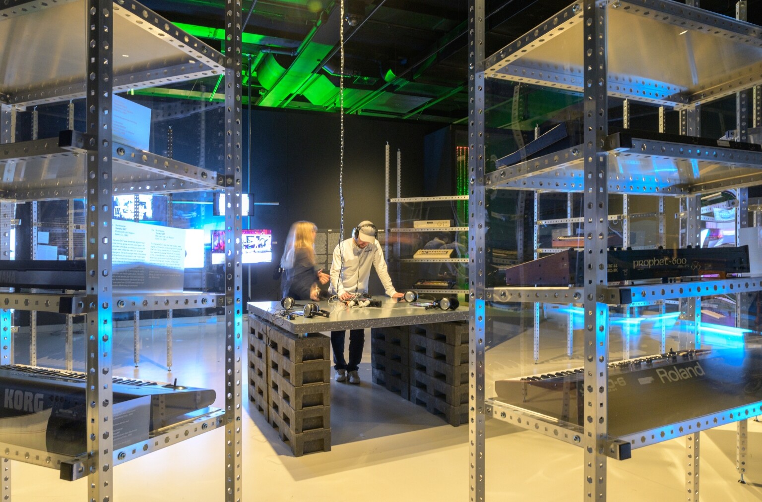 Twee mensen maken gebruik van een drumcomputer simulatie op een ipad in een tentoonstelling.
