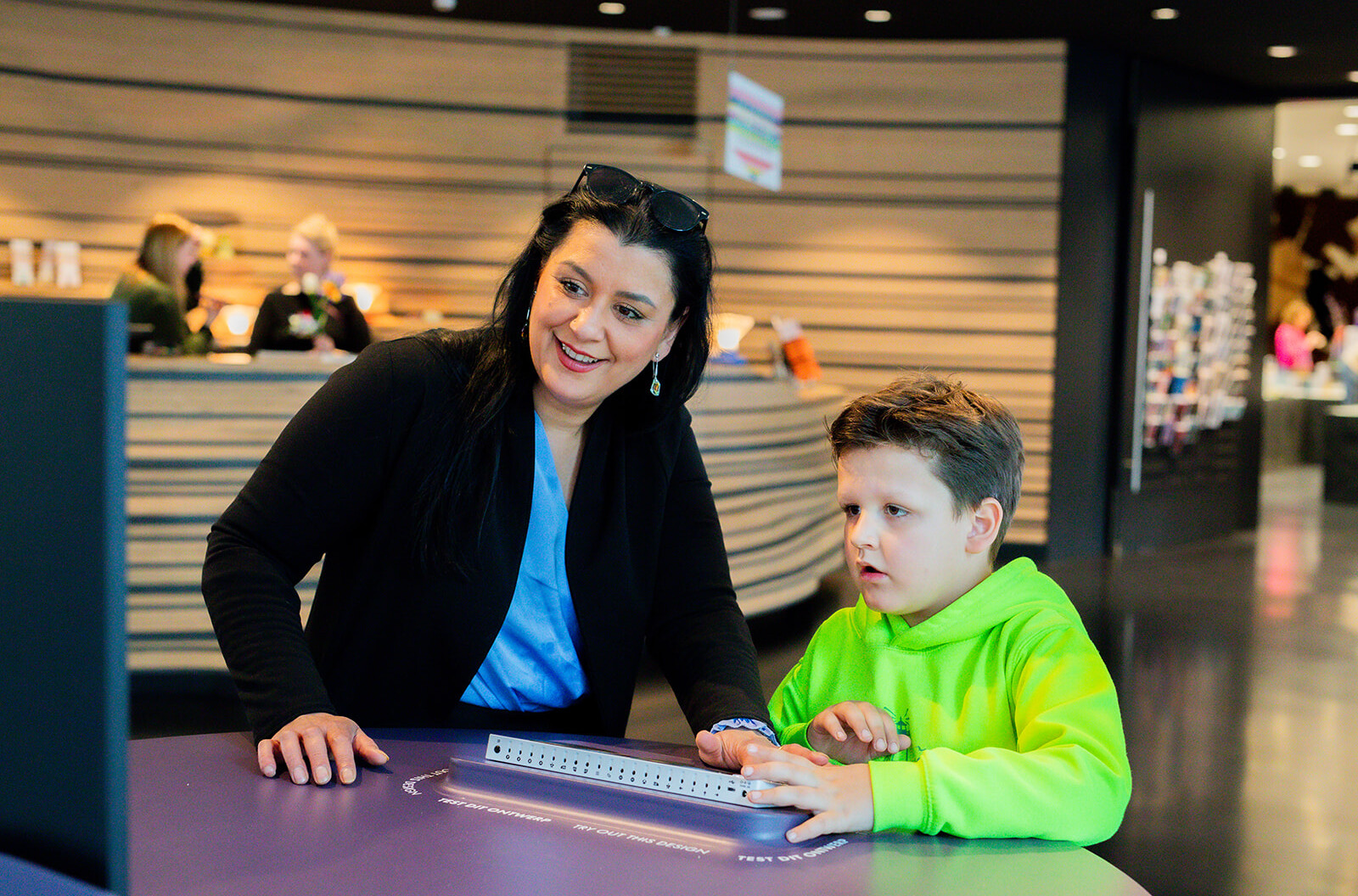 Een moeder en zoon spelen met een speciale Xbox controller in het OntwerpStation.