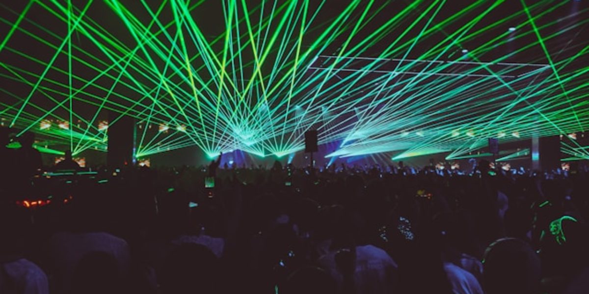 Een menigte mensen bij een concert met groene laserlichten.