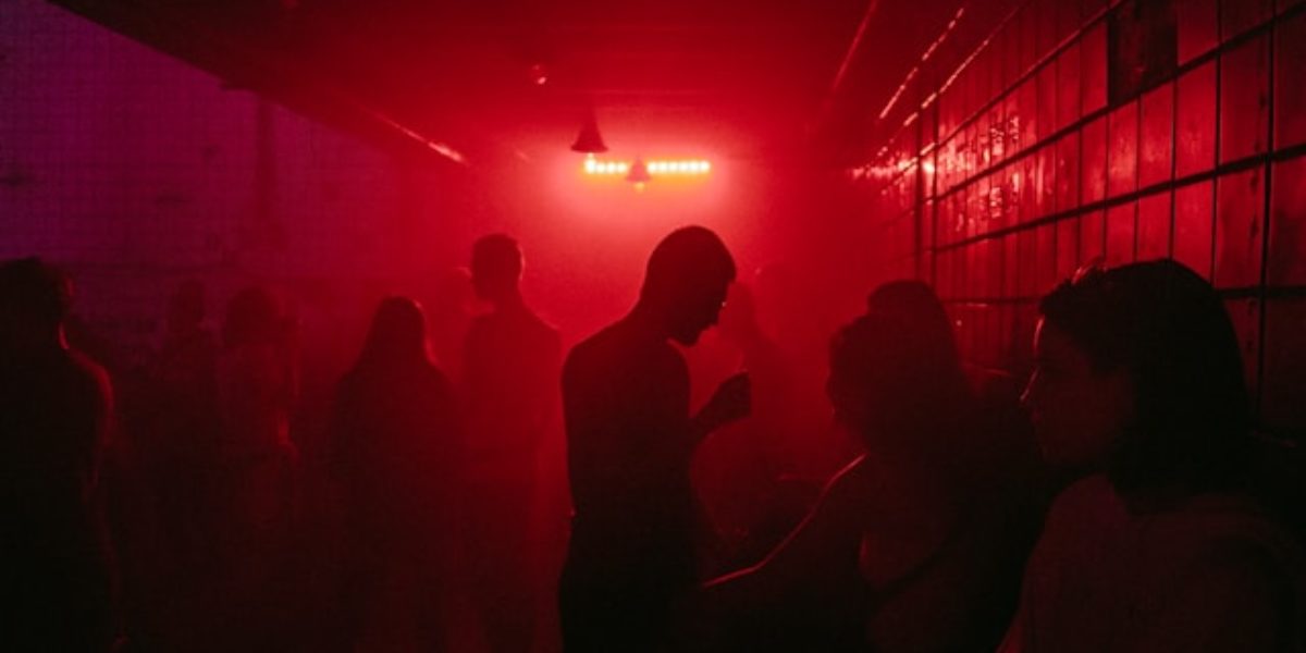 Mensen staan in een donkere kamer met rode verlichting.