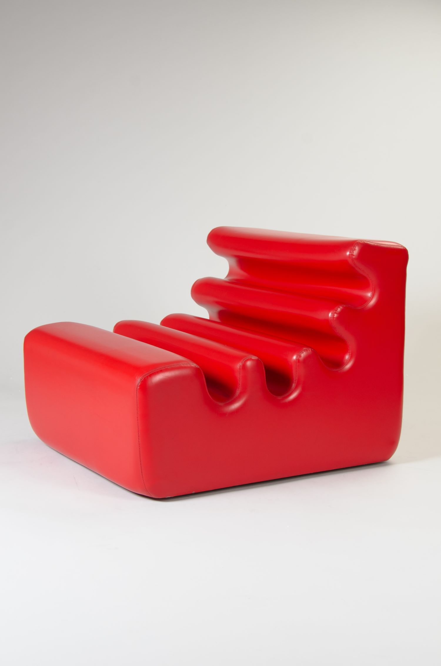 This is a photo of seating furniture. It is a red plastic piece of furniture, made by Liisi Beckmann. 