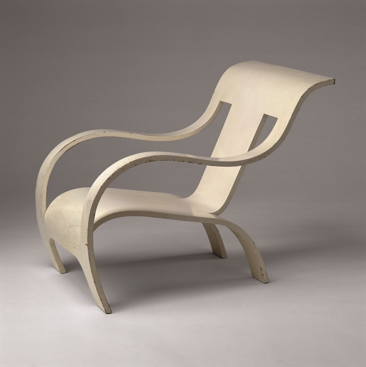 This is a picture of a cream colored armchair. The chair is made out of one piece of plywood by Gerald Summers. 