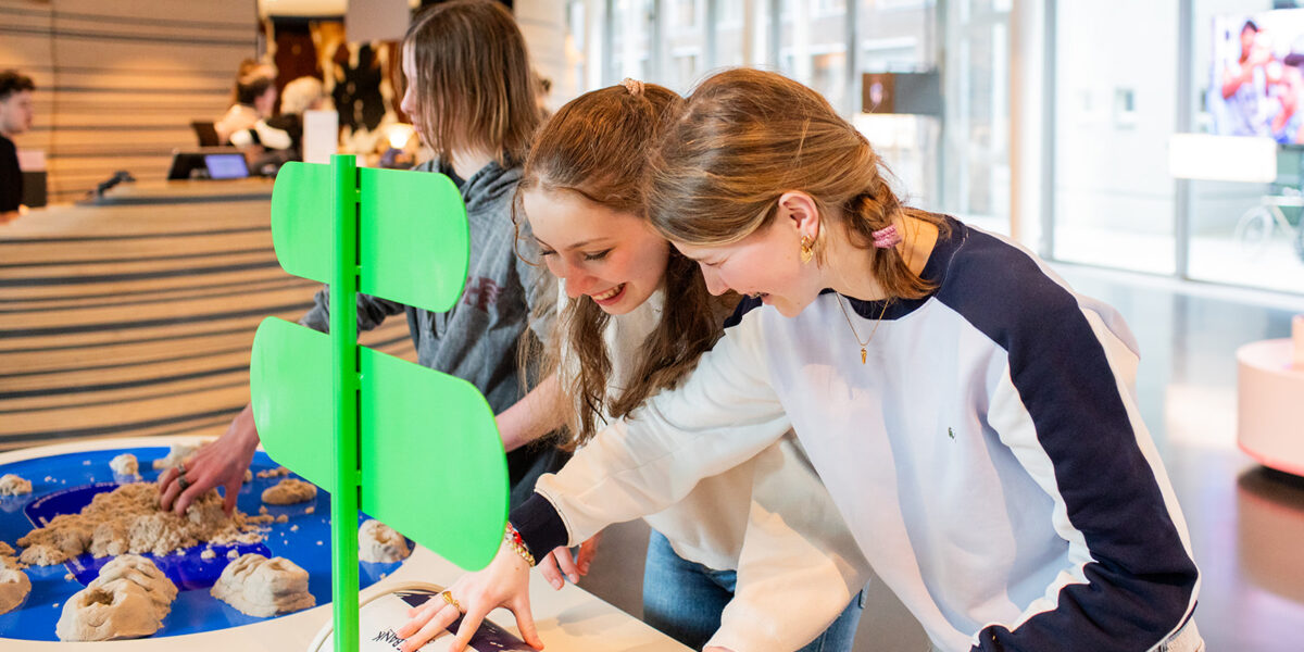 Twee meisjes zijn samen druk bezig in het OntwerpStation. Waarbij ze lachen door iets wat ze tegen elkaar zeggen.