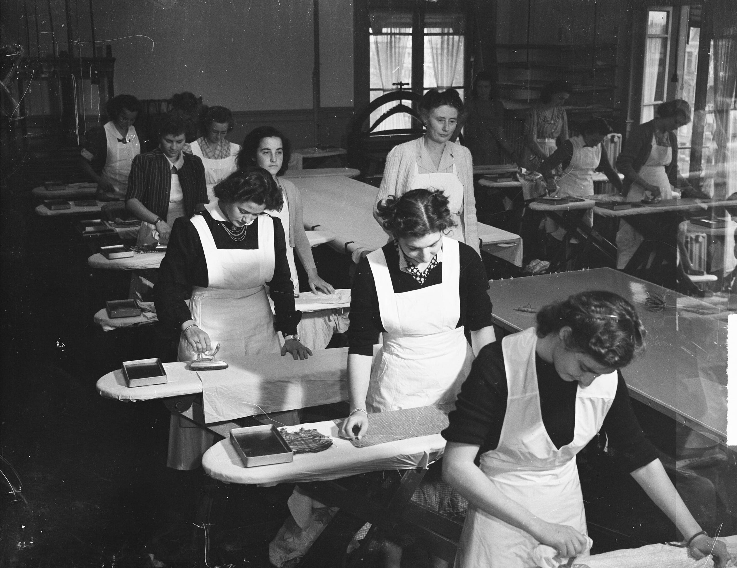 Historische foto. Meisjes krijgen les in strijken op de Amsterdamse Huishoudschool.